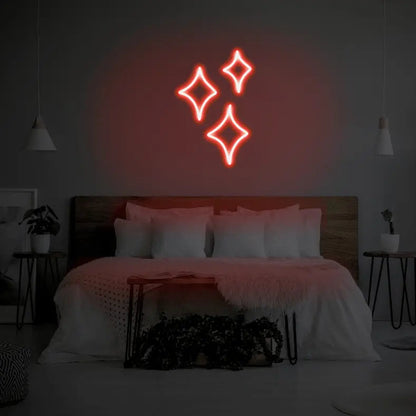 Sparkle LED Neon Light Sign in red, featuring three outlined sparkle shapes illuminated above a bed.