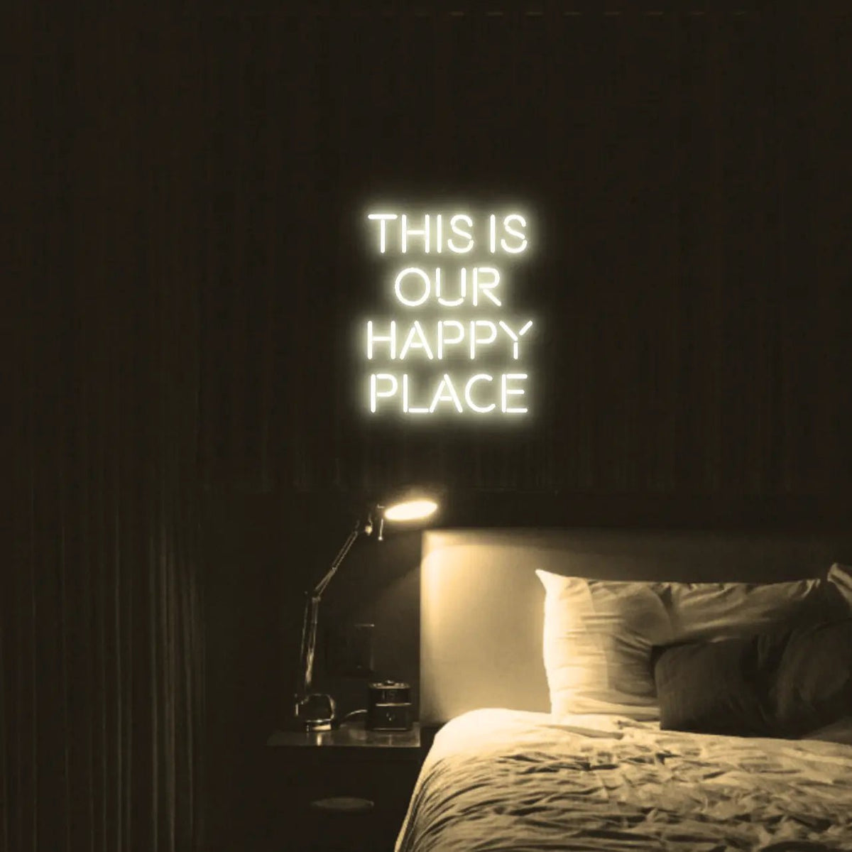 This is our happy place LED Neon Light Sign in warm white, featuring stacked block lettering illuminated above a bed.