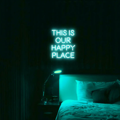 This is our happy place LED Neon Light Sign in turquoise, featuring stacked block lettering illuminated above a bed.