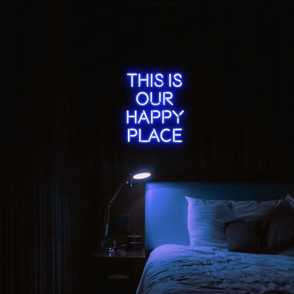 This is our happy place LED Neon Light Sign in blue, featuring stacked block lettering illuminated above a bed.
