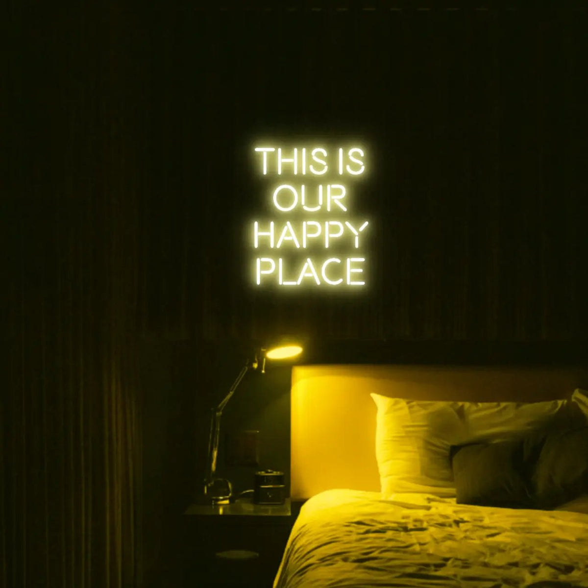 This is our happy place LED Neon Light Sign in yellow, featuring stacked block lettering illuminated above a bed.