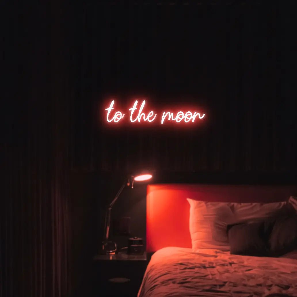 To The Moon LED Neon Light Sign in red, featuring script lettering illuminated above a bed in a dark bedroom.