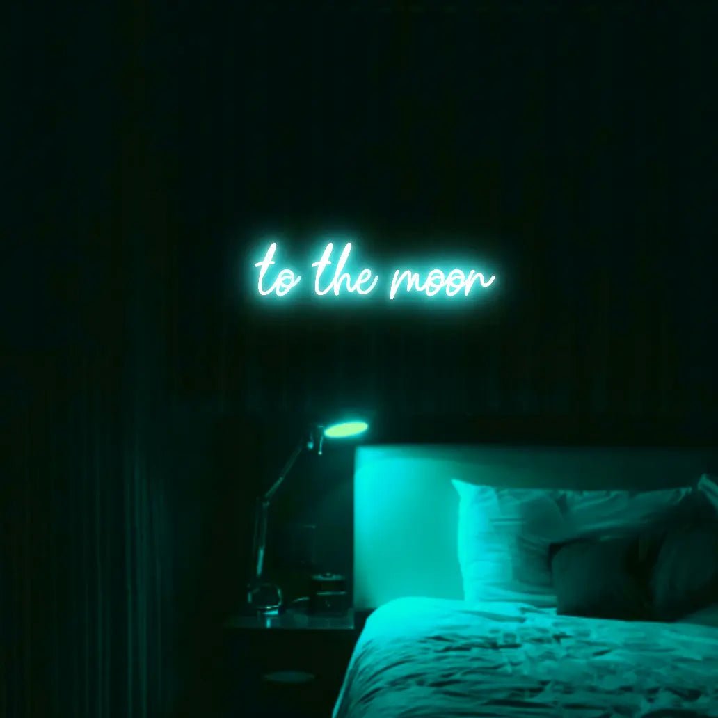 To The Moon LED Neon Light Sign in turquoise, featuring script lettering illuminated above a bed in a dark bedroom.