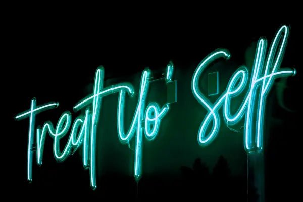 Treat Yo'self LED Neon Light Sign in turquoise, featuring script lettering viewed at an angle against a dark wall.