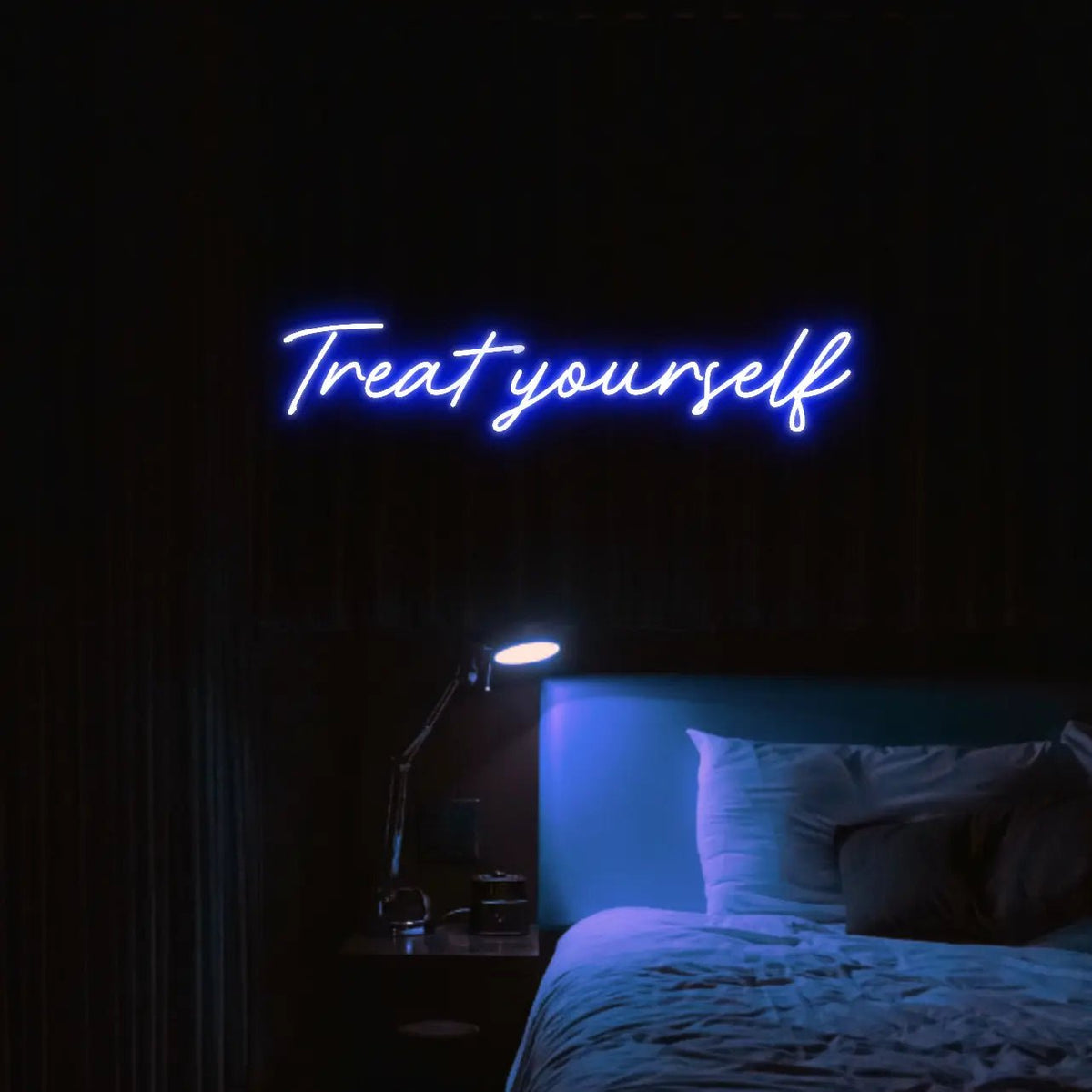 Treat Yourself LED Neon Light Sign in blue, featuring script lettering illuminated above a bed in a dark bedroom.