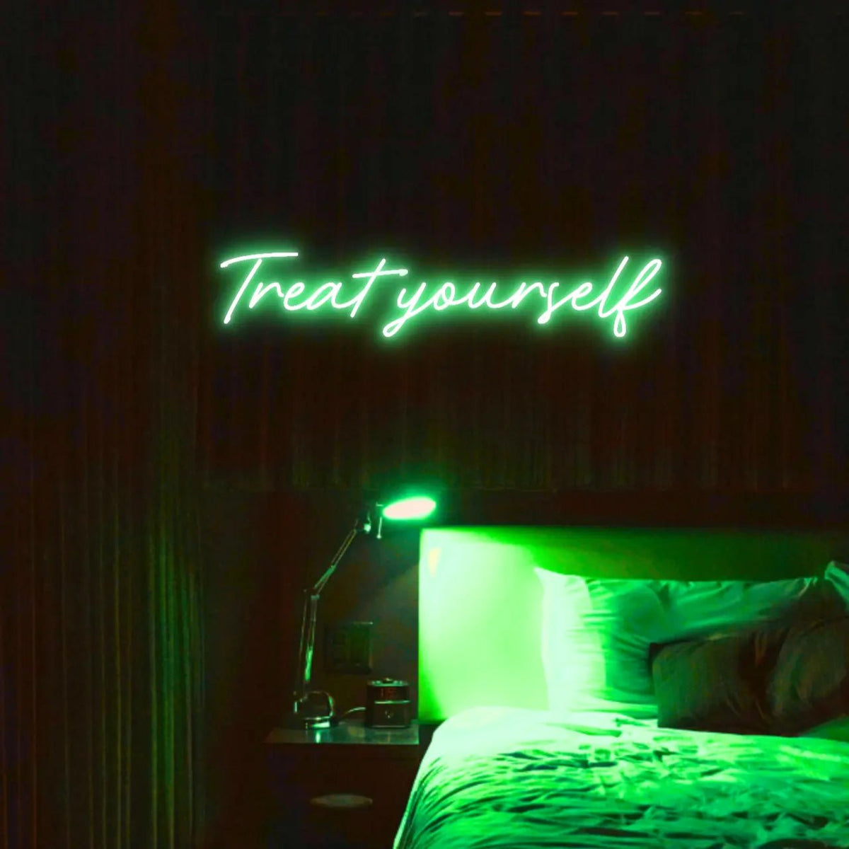 Treat Yourself LED Neon Light Sign in green, featuring script lettering illuminated above a bed in a dark bedroom.