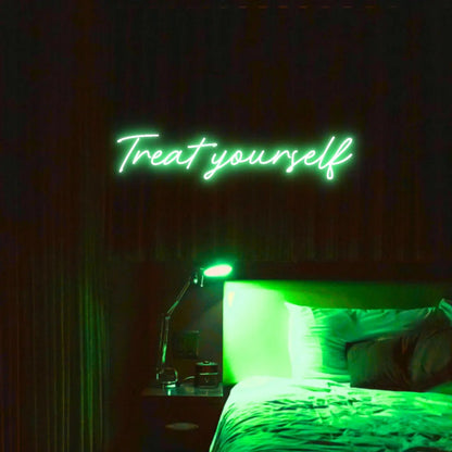 Treat Yourself LED Neon Light Sign in green, featuring script lettering illuminated above a bed in a dark bedroom.