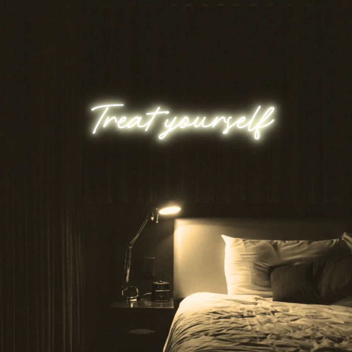 Treat Yourself LED Neon Light Sign in warm white, featuring script lettering illuminated above a bed in a dark bedroom.