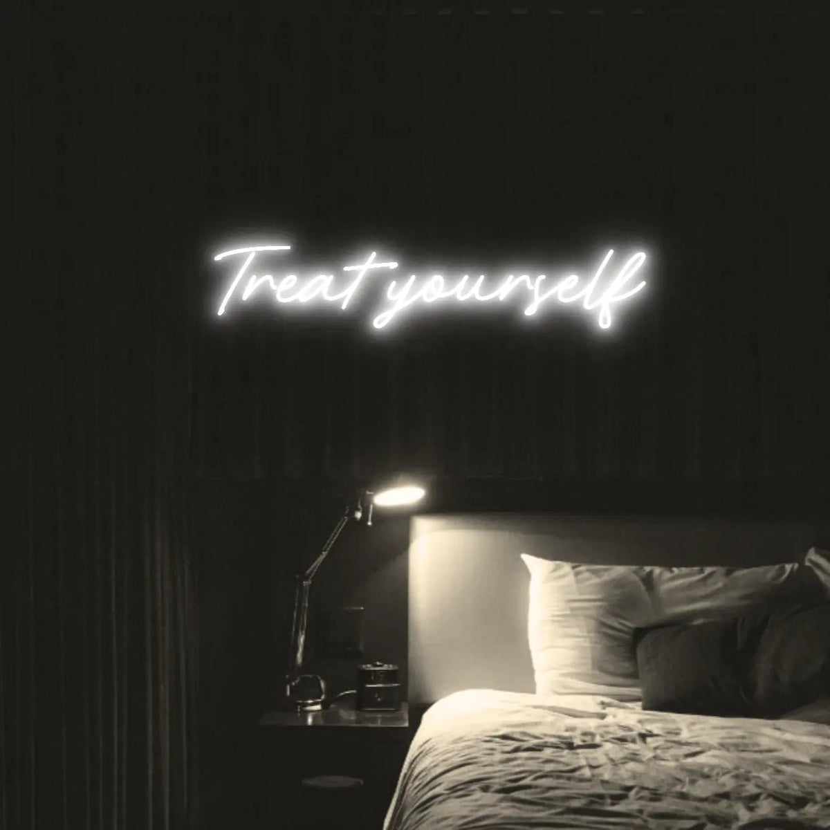 Treat Yourself LED Neon Light Sign in white, featuring script lettering illuminated above a bed in a dark bedroom.
